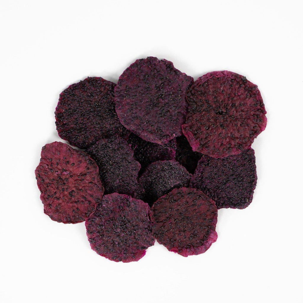 Dried red dragon fruit slices stacked on white background